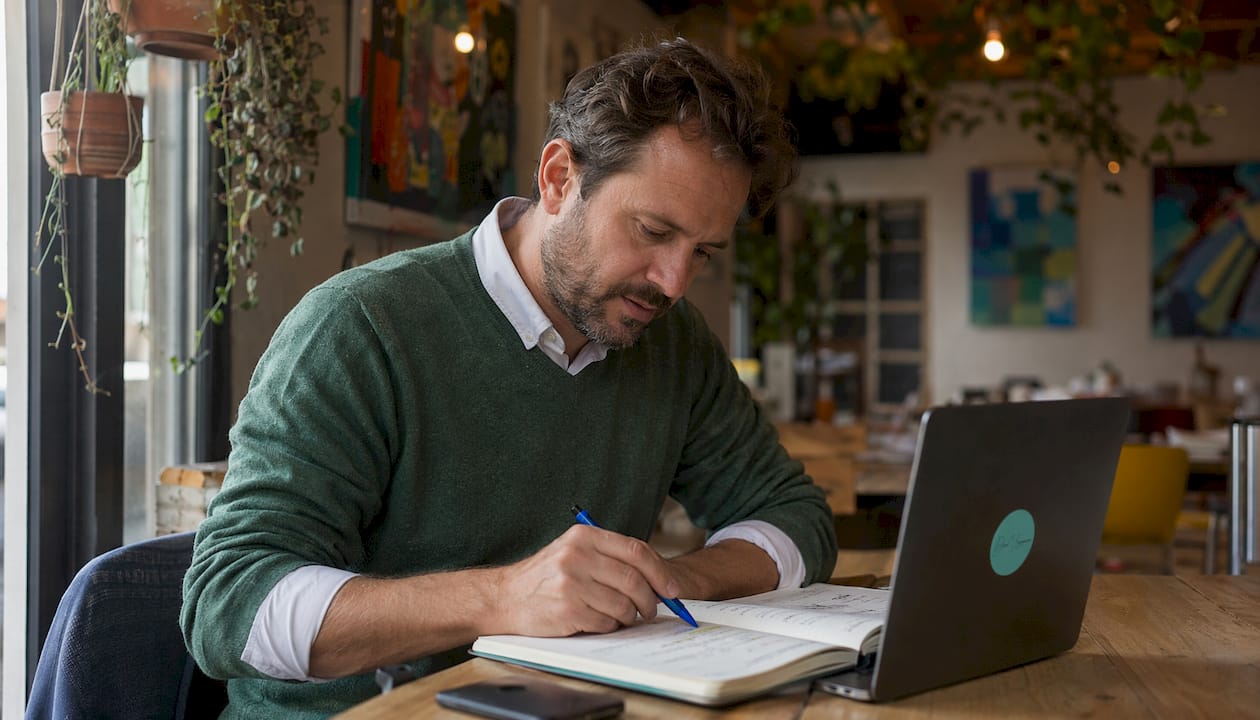 Un homme consulte ses cours et prend des notes sur une plateforme d’apprentissage en ligne.