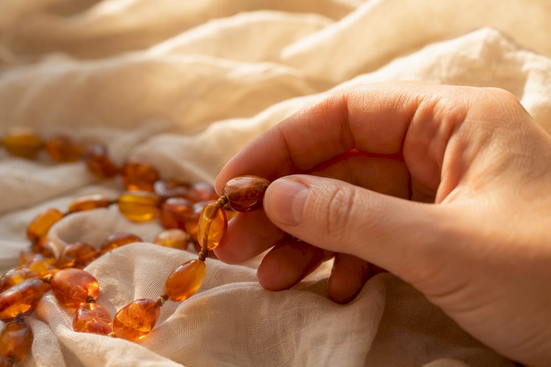 Hand inspecting amber necklace cord and beads