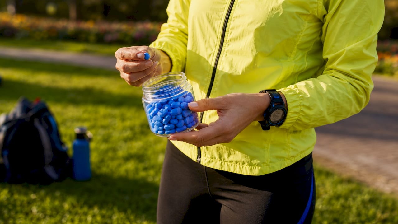 Coach holding electrolyte tablets at athletic track