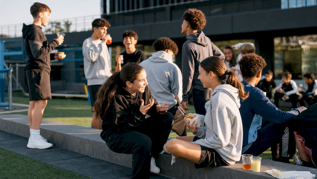 Youth athletes socializing at sports event outdoors