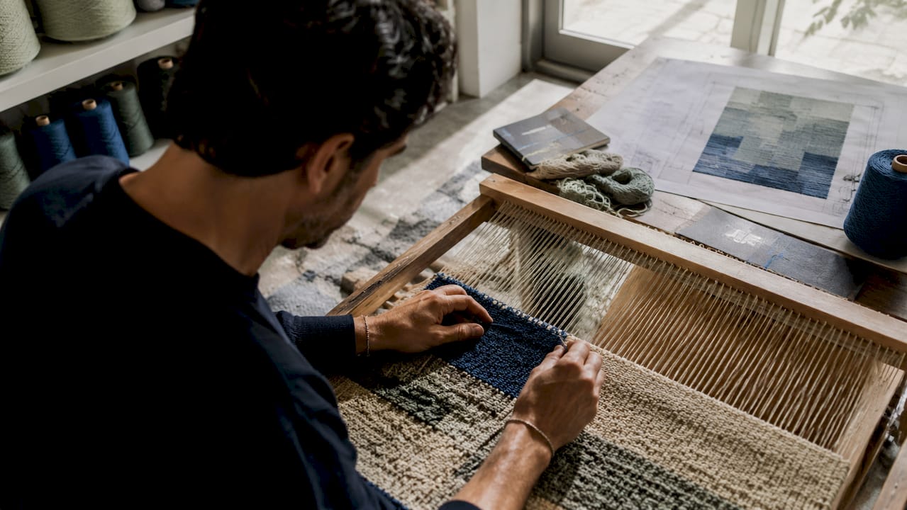 Close-up of hands weaving bespoke luxury rug
