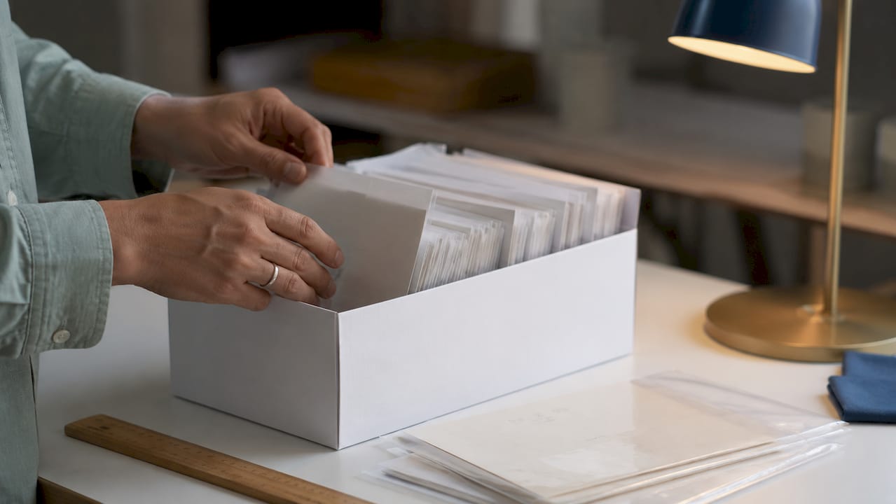 Hands archiving provenance documents in acid-free sleeves