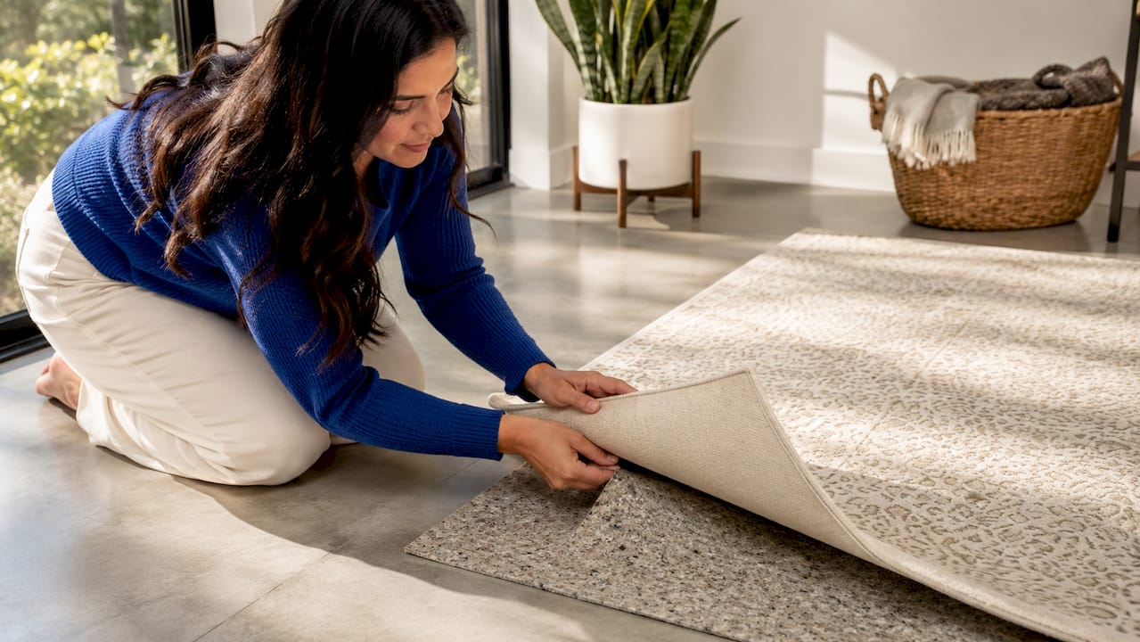 Hands placing rug pad under luxury rug