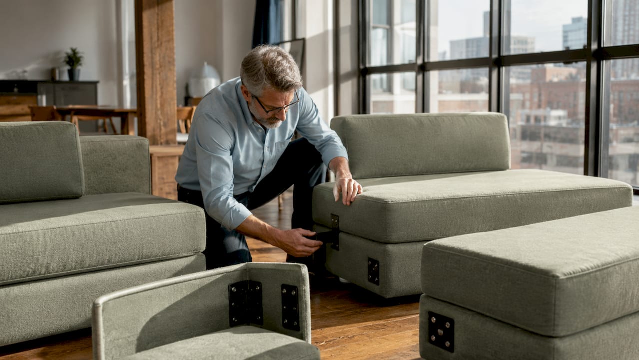 Hands showing modular sofa connection hardware close-up
