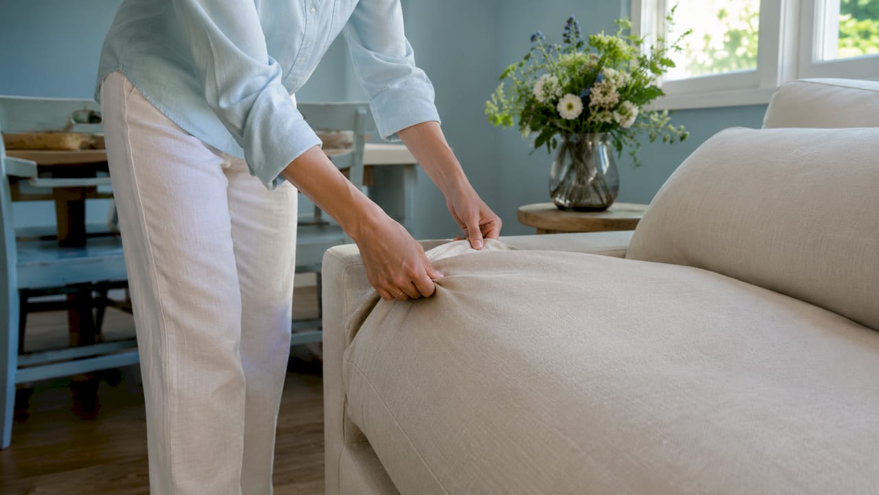 Hands fitting slipcover on sofa cushion
