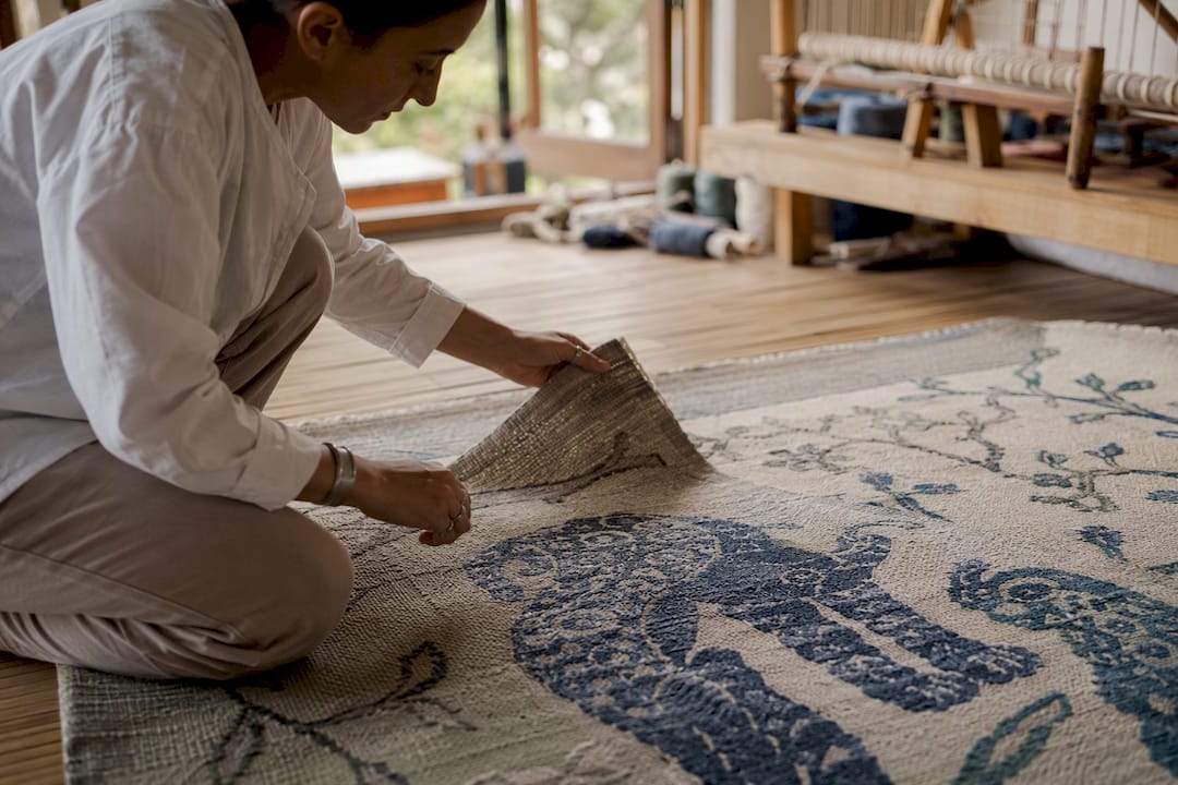 Hands aligning pattern on bespoke handmade rug