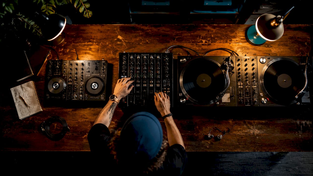 Van bovenaf gefotografeerd: een aantal verschillende DJ-mixers voor beginners liggen uitgestald op tafel.