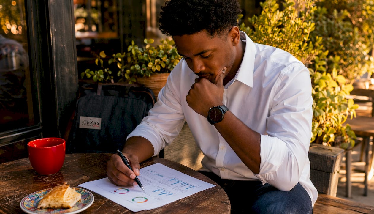 Hands holding credit report and smartphone at café table