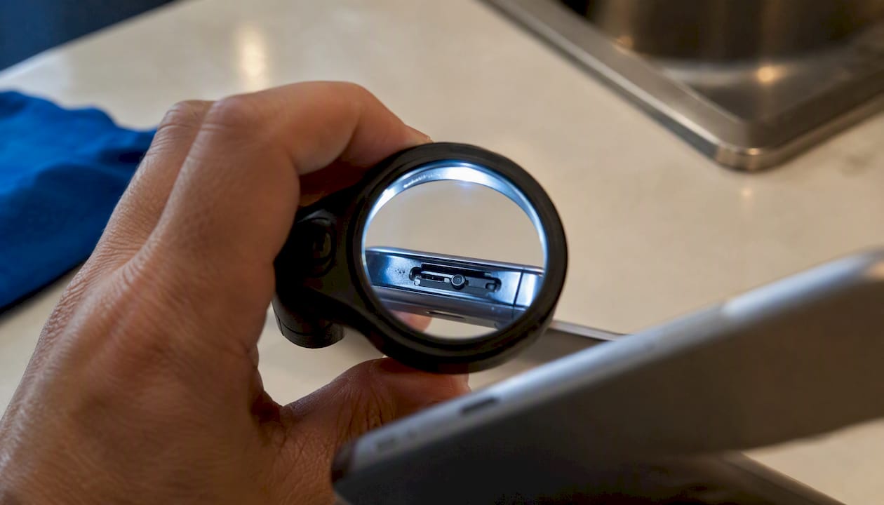Met een vergrootglas wordt het simkaartslot nauwkeurig gecontroleerd.