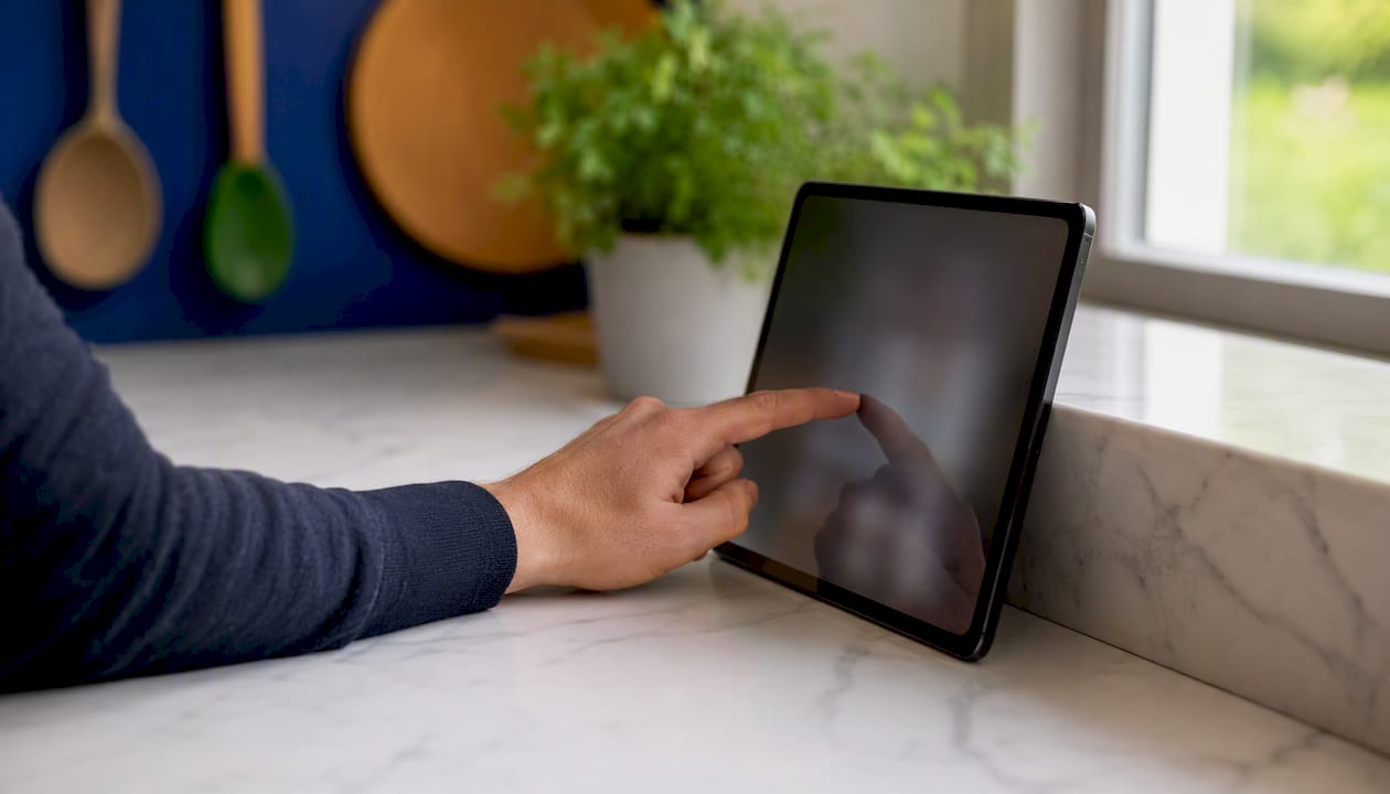 Een hand tikt een telefoonnummer in op het contactenscherm van een iPad.