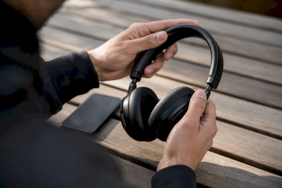 Handen die een Bluetooth-hoofdtelefoon vasthouden bij een smartphone