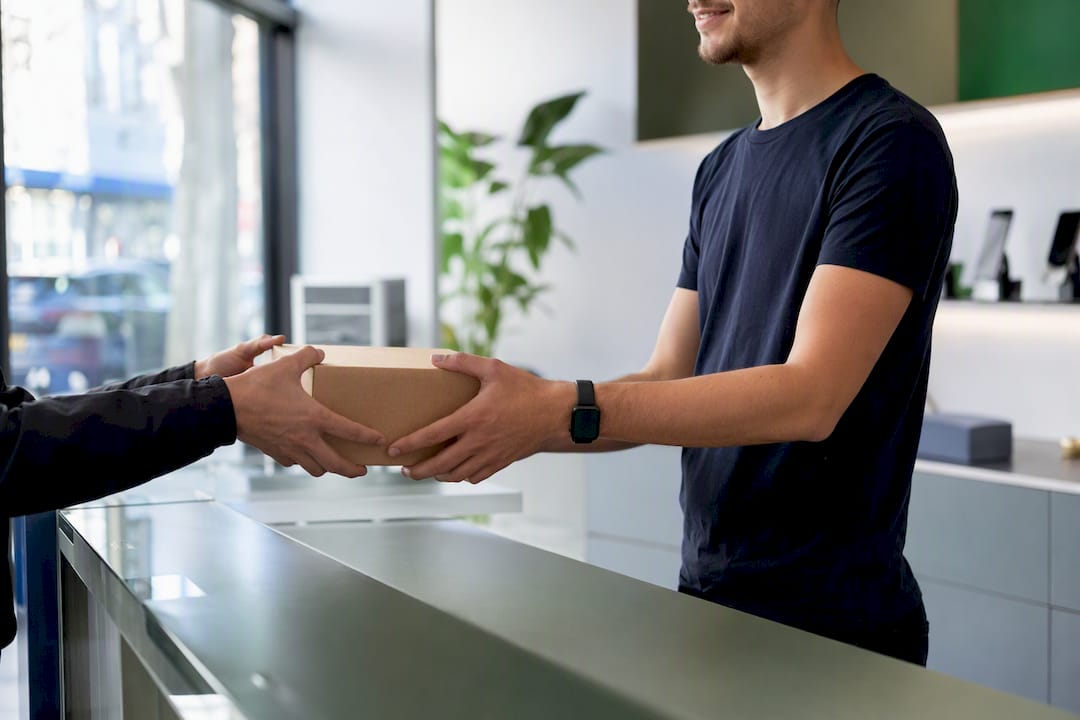 Handen wisselen pakketdoos uit in moderne winkel