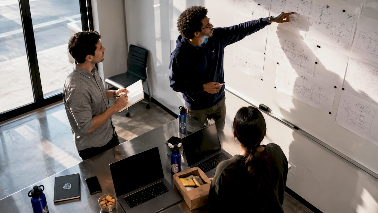 Software team discussing workflows by corkboard