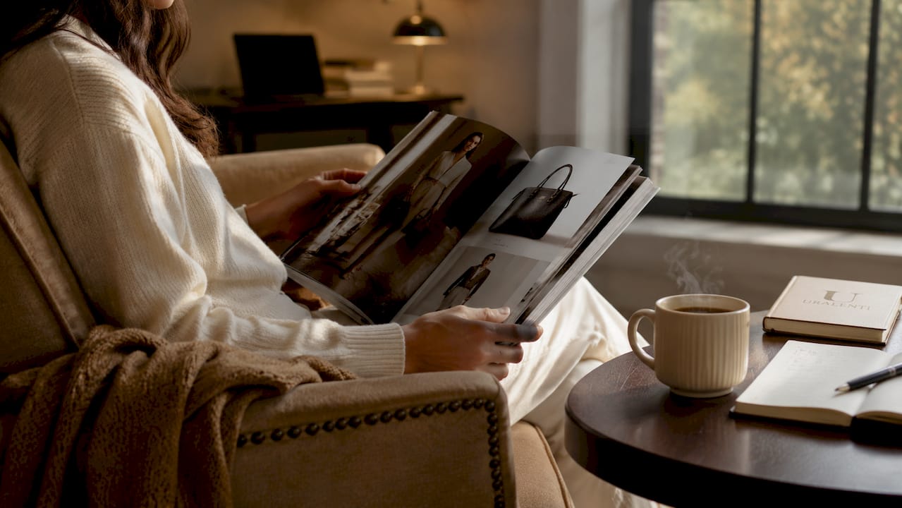 Hands reviewing luxury fashion catalogue overhead