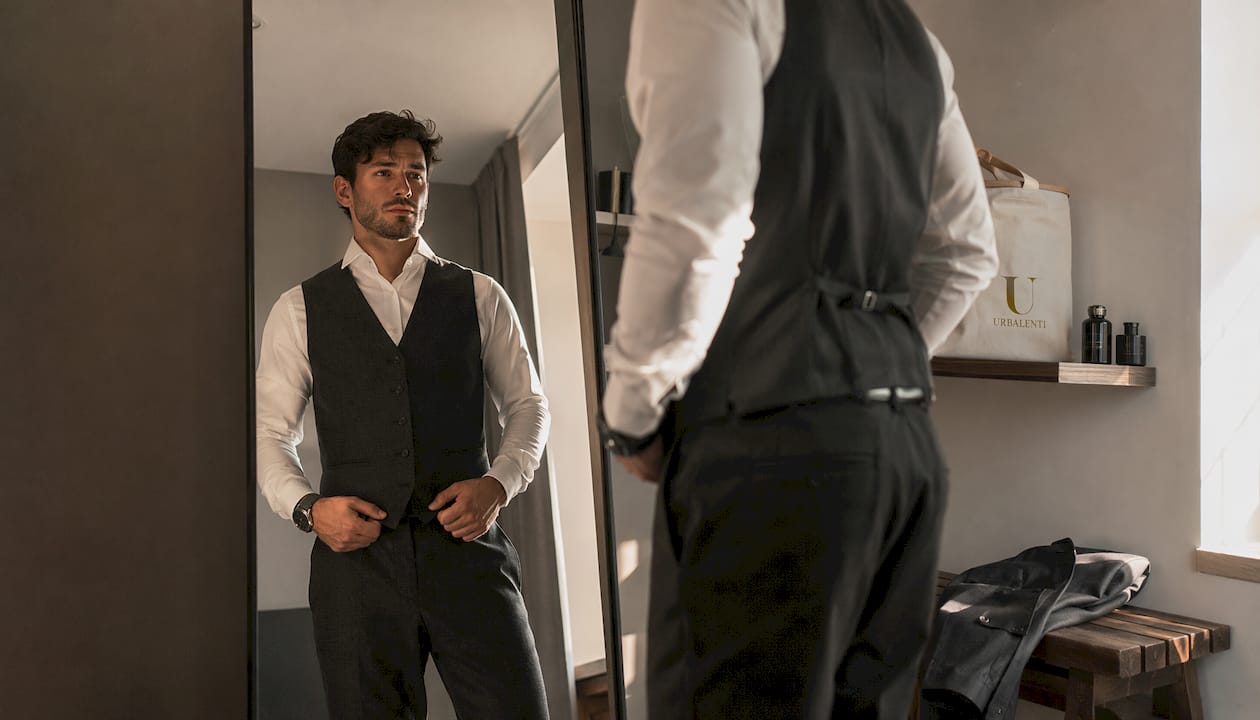 Man trying on designer vest in boutique mirror