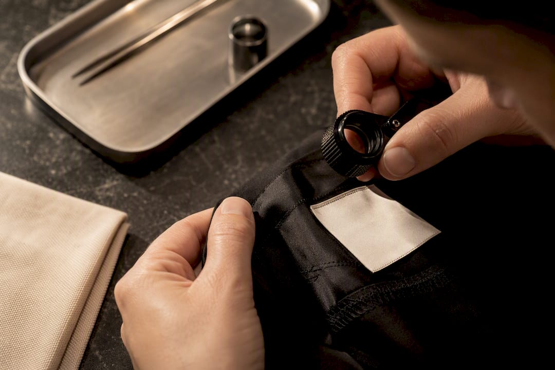 Authenticator inspecting garment tag and stitching