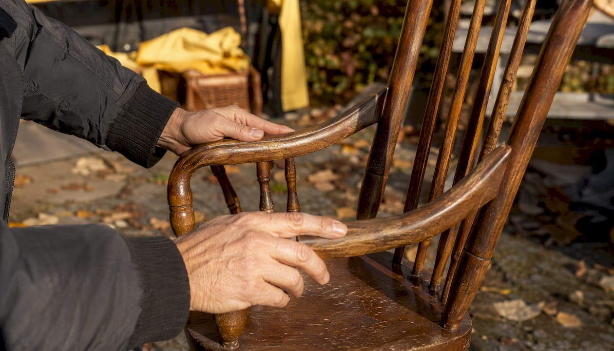 Hands inspecting vintage chair detail at yard sale