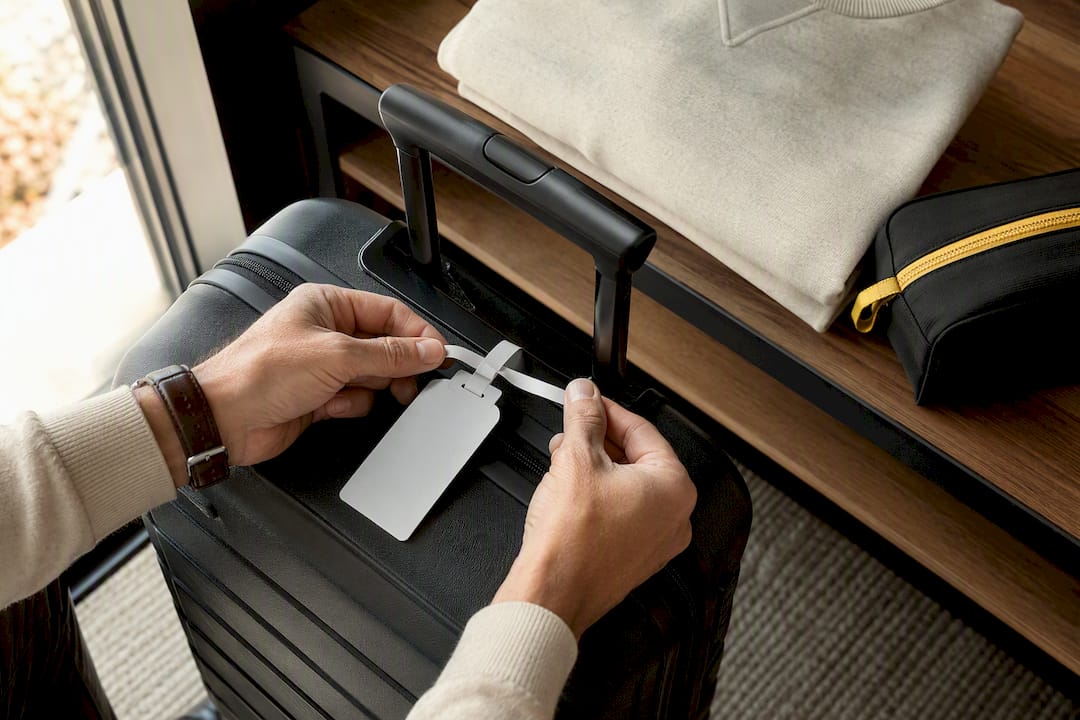Hands fastening a luggage tag to suitcase