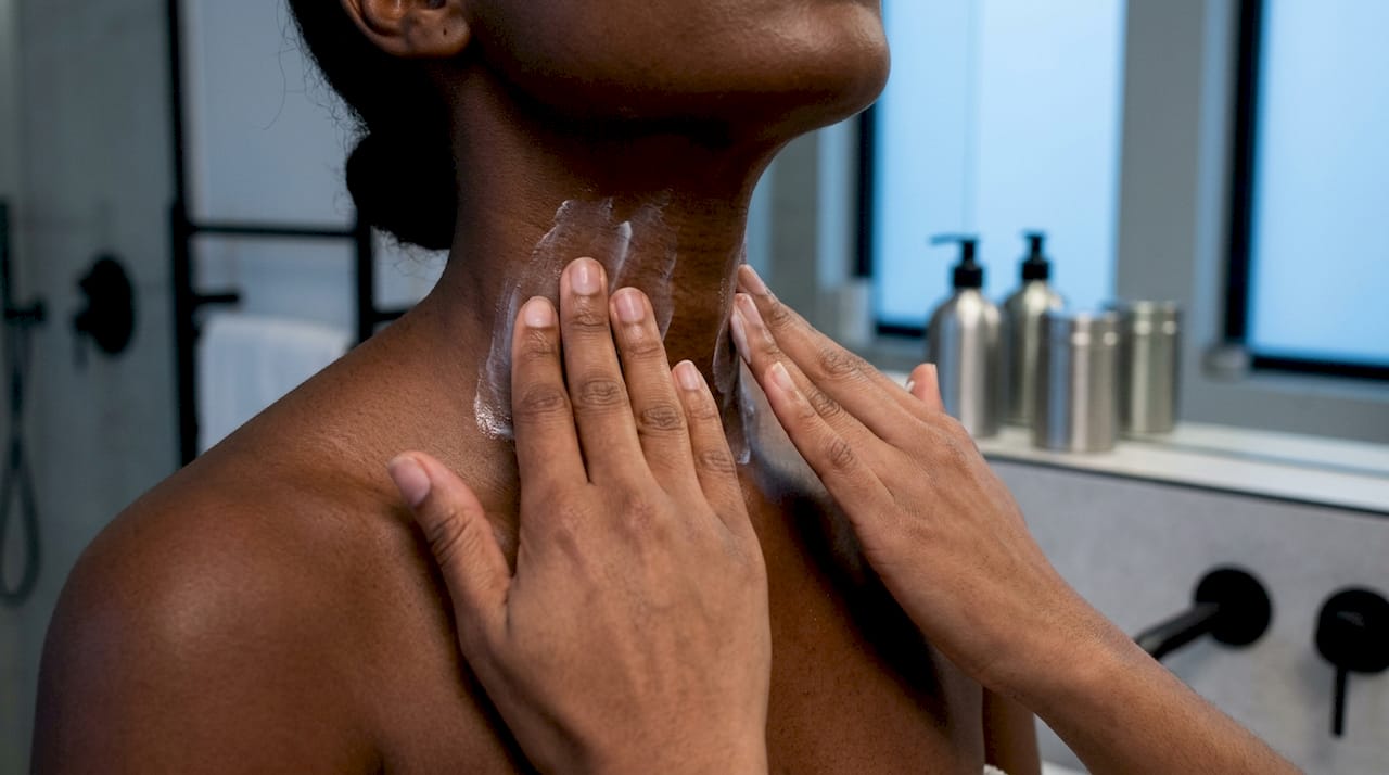 Close-up of hands applying cream on neck skin