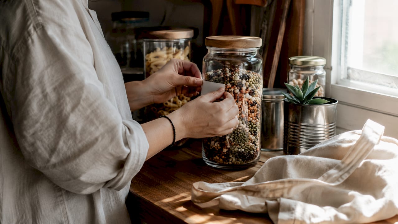 Hands labeling repurposed glass jars