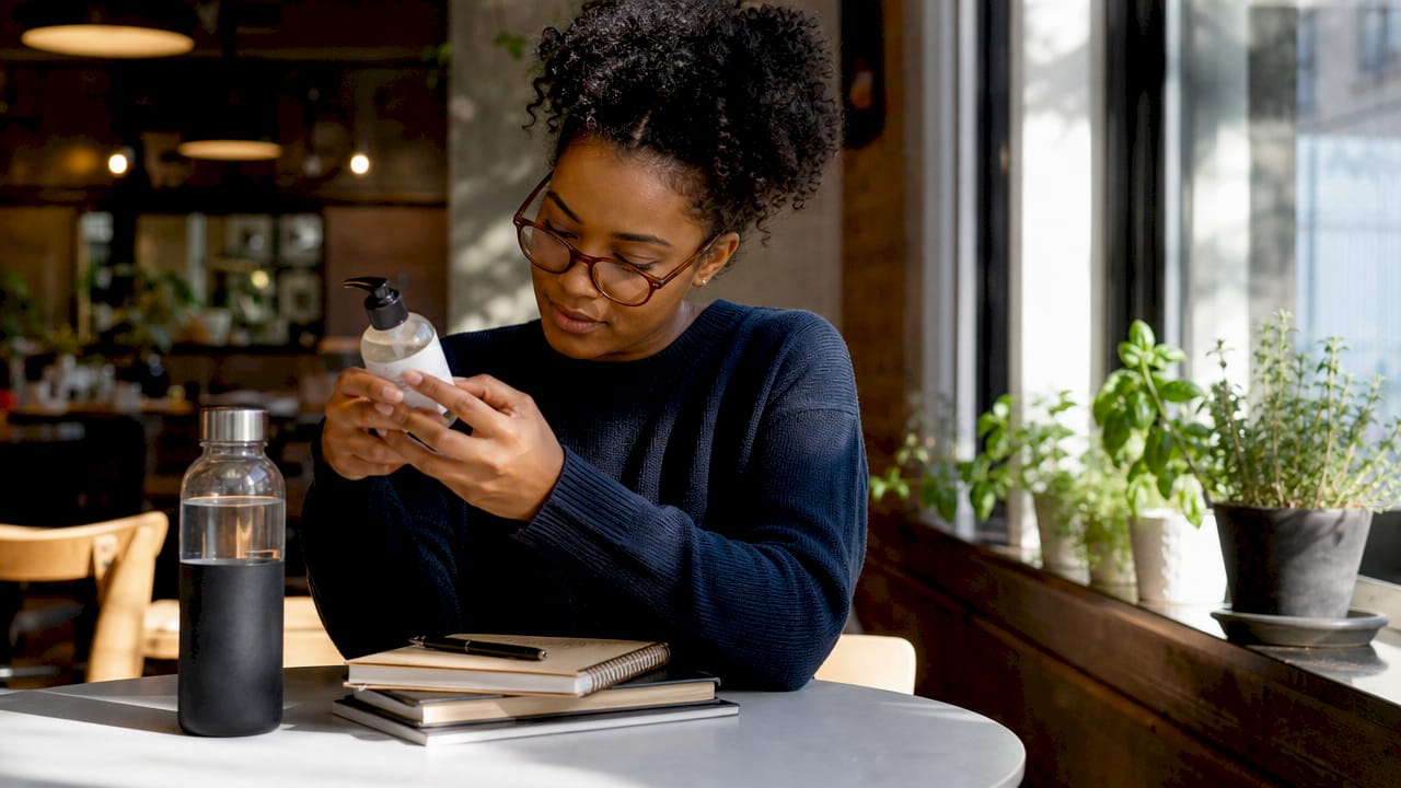 Woman reading clean beauty product label at home
