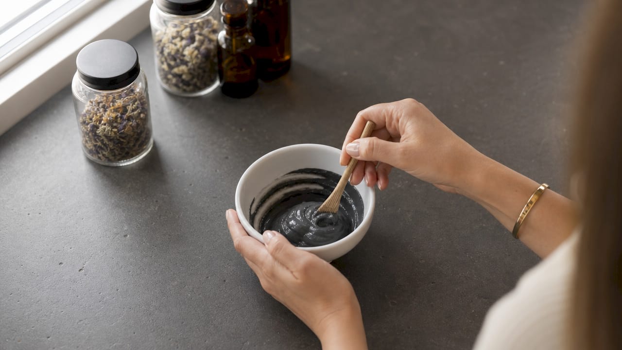Close-up applying charcoal face mask hands