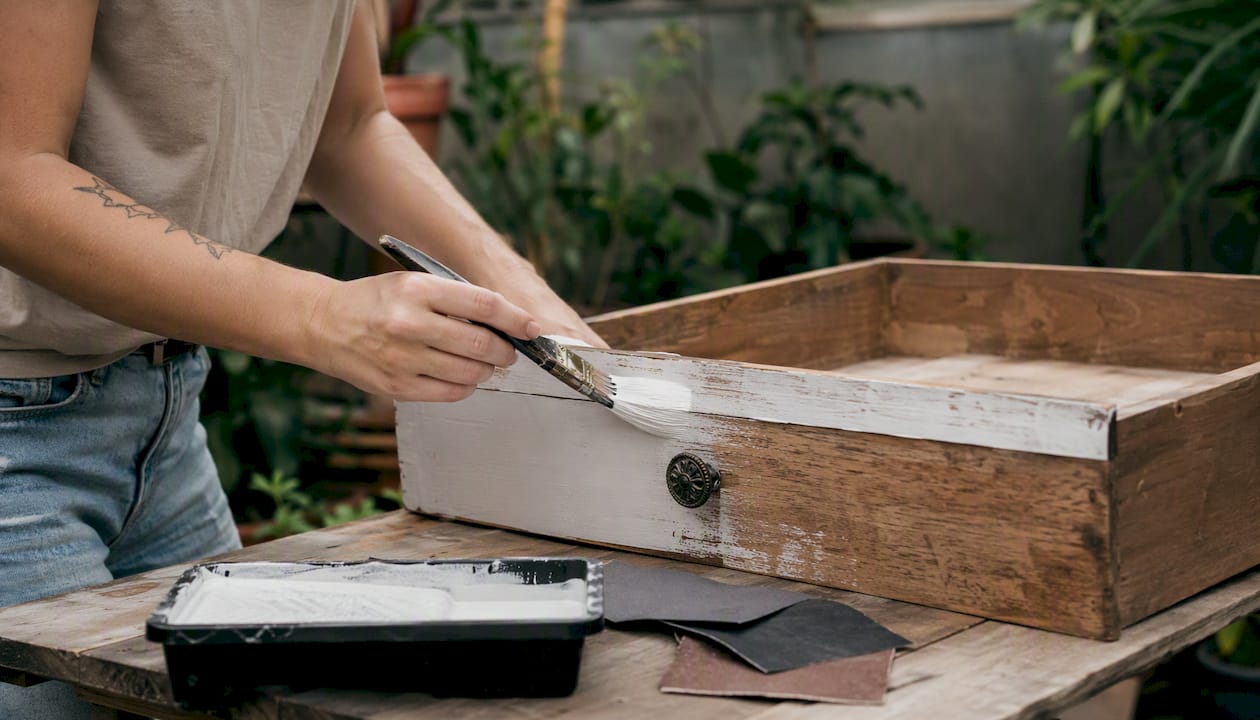Hands painting upcycled wooden drawer shelf
