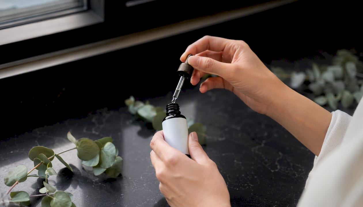 Hands inspecting cosmetic bottle dropper