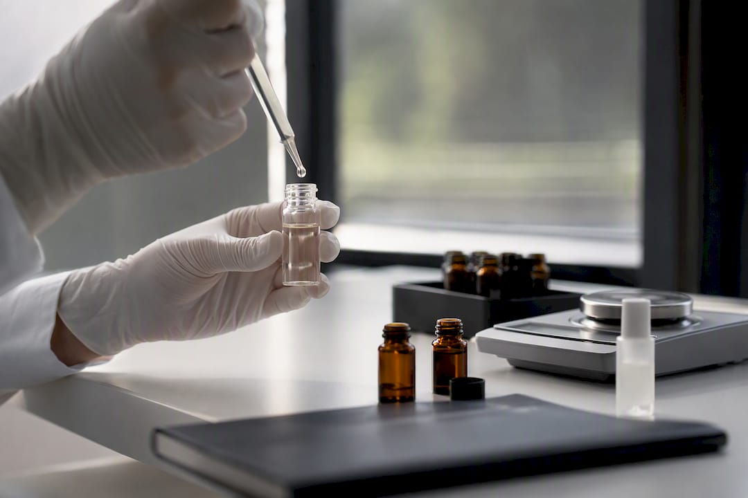 Hands handling fragrance vial in minimalist lab