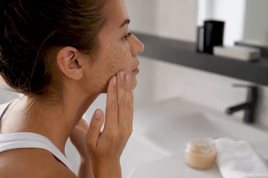 Hands applying gentle facial exfoliant scrub