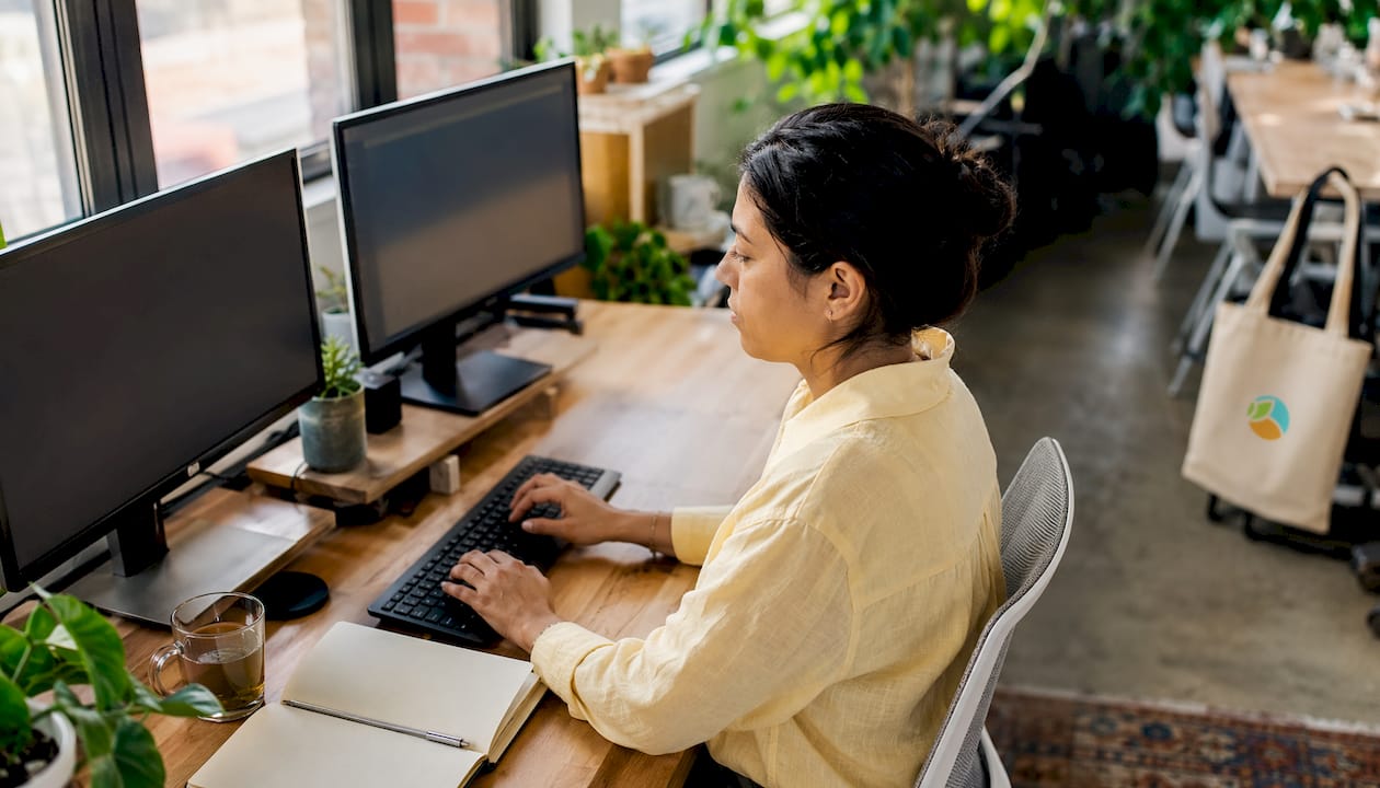 Woman working at dual monitors in home office
