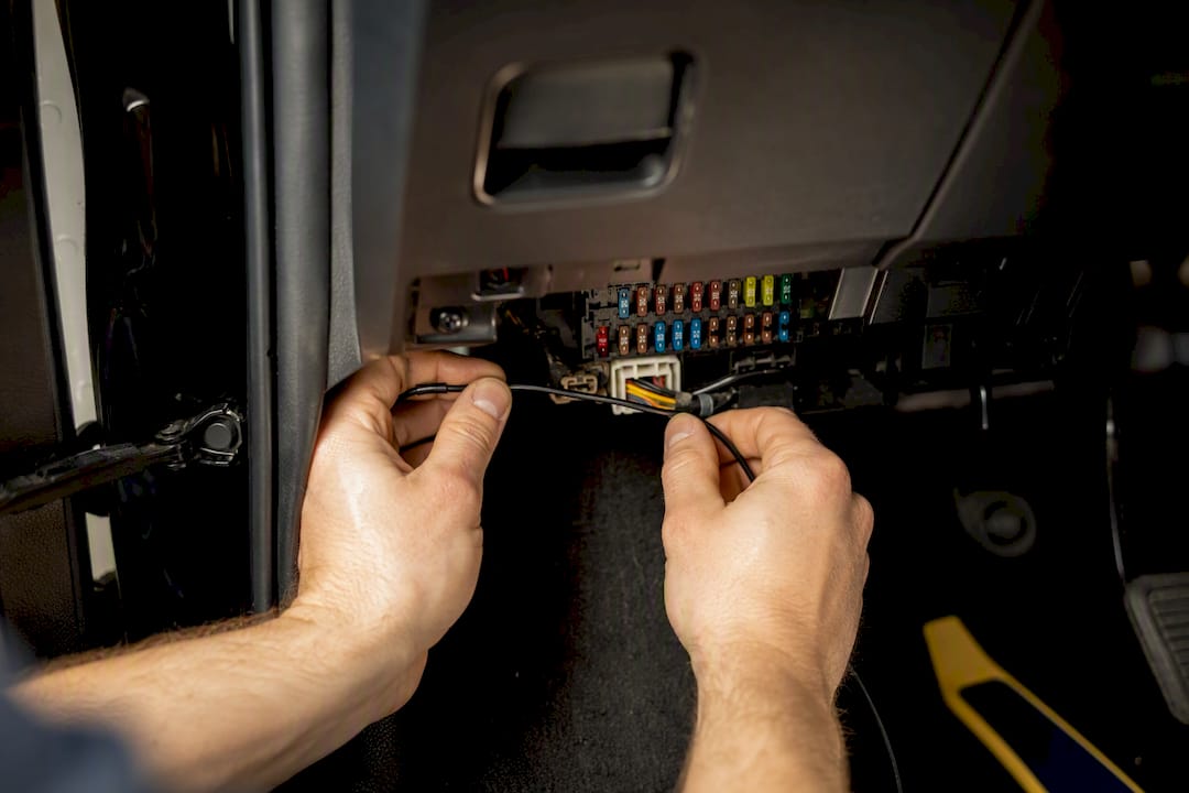Hands routing a dash cam hardwire lead