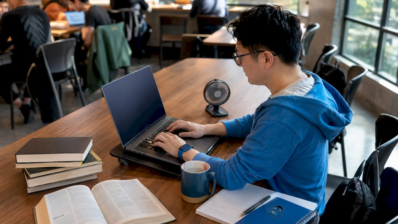 Man typing on budget laptop with cooling pad