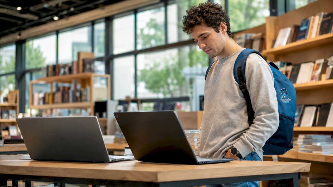 Student comparing laptops at dorm desk