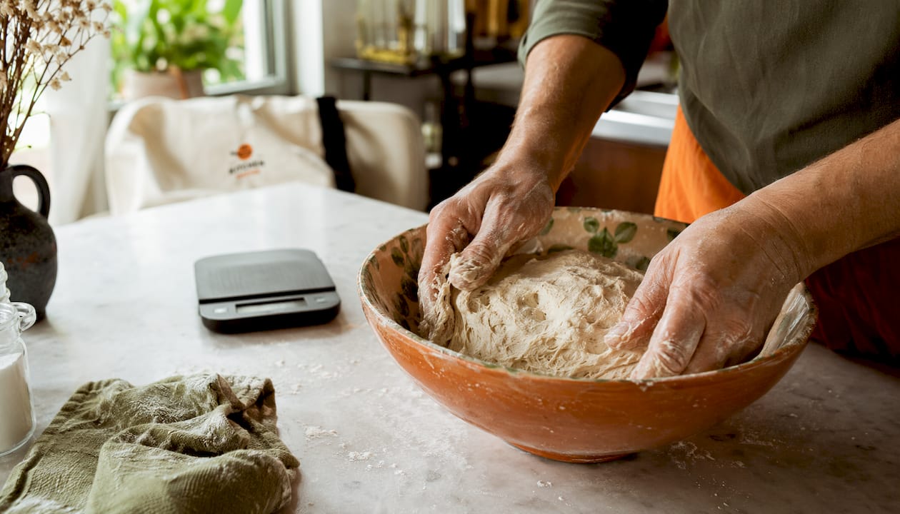 Hands shaping fermenting dough in bowl