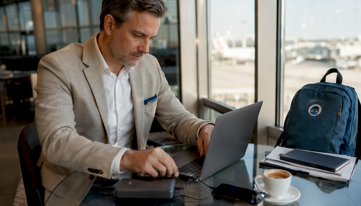 Business traveler charging laptop and phone with power bank