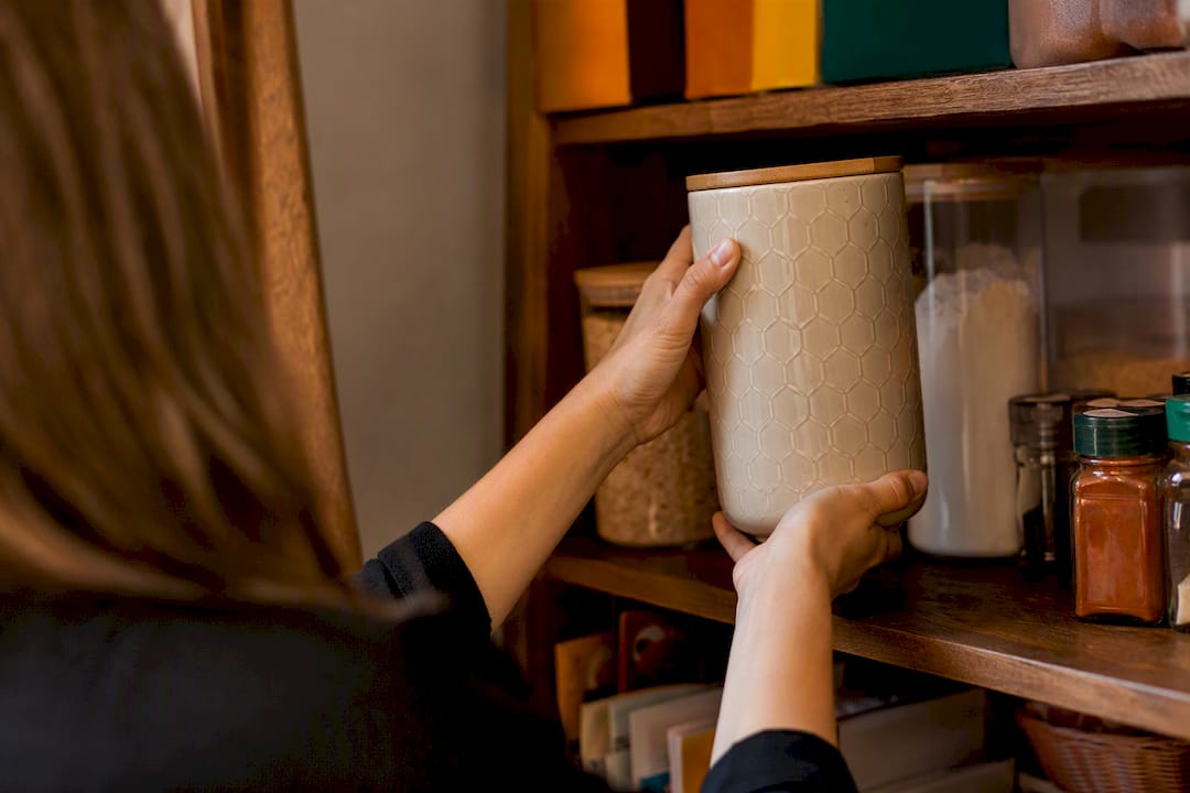 Hands arranging slim bins in pantry shelf