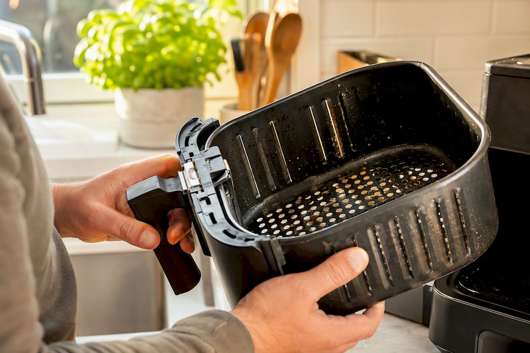 Hands inspecting air fryer basket for damage