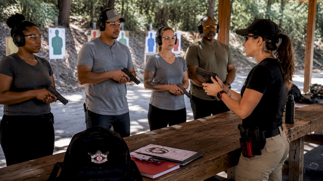 Firearms instructor teaching safe handgun handling outdoors