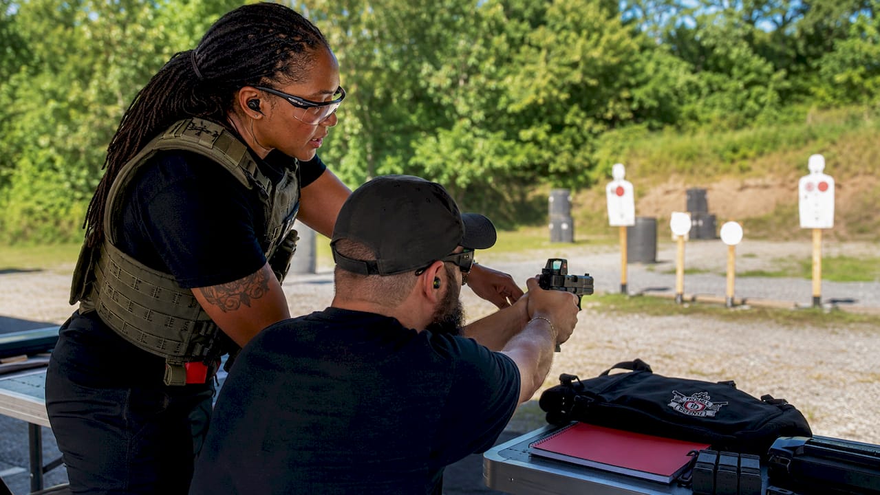 Instructor guiding low vision student at firearm range