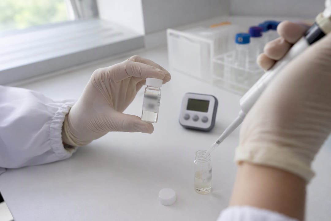 Muestra de saliva en vial siendo manipulada en laboratorio