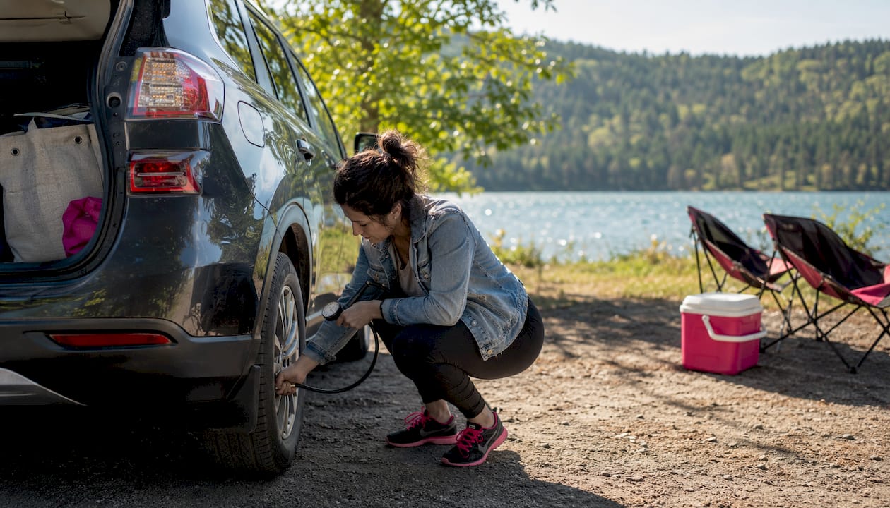 Woman checking SUV tire on driveway