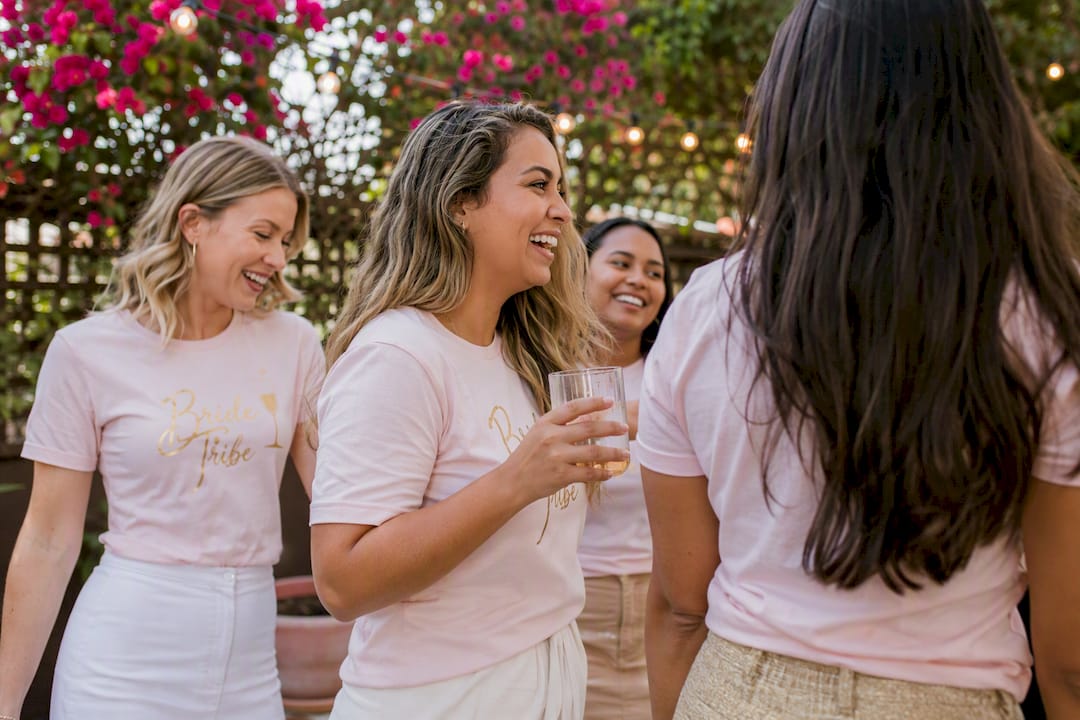 Women in matching pastel bachelorette shirts on rooftop