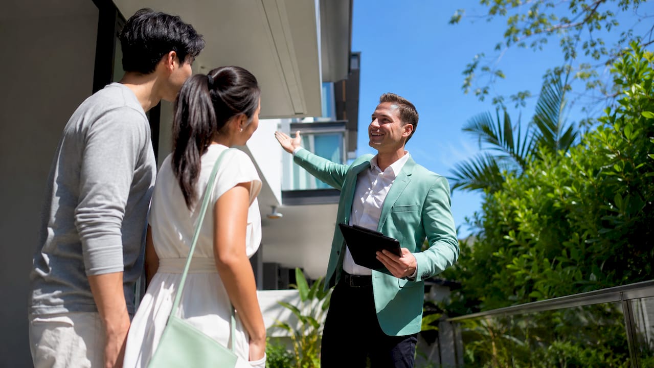 Agent and buyers outside new home in ACT suburb