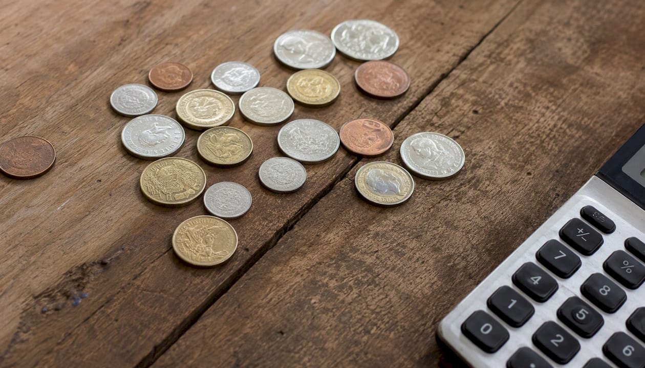 Coins on wooden table next to calculator