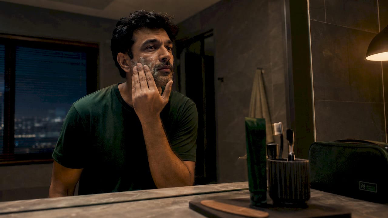 Man applying skincare in bathroom mirror