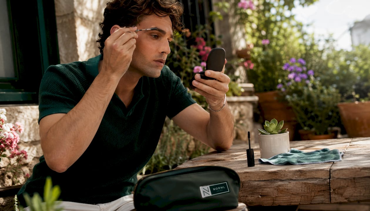 Man grooming brows with clear gel in home office