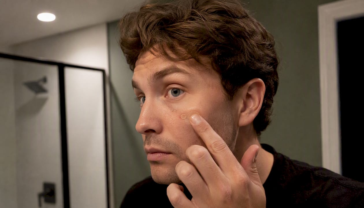 Close-up of fingertip tapping concealer on cheek