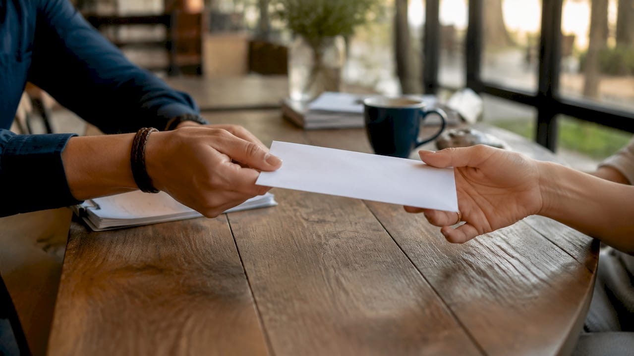Hands exchanging real estate commission payment envelope