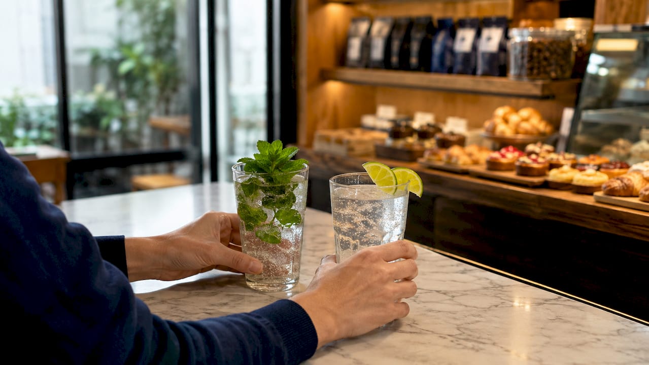 Hands holding glasses of sparkling water with snacks